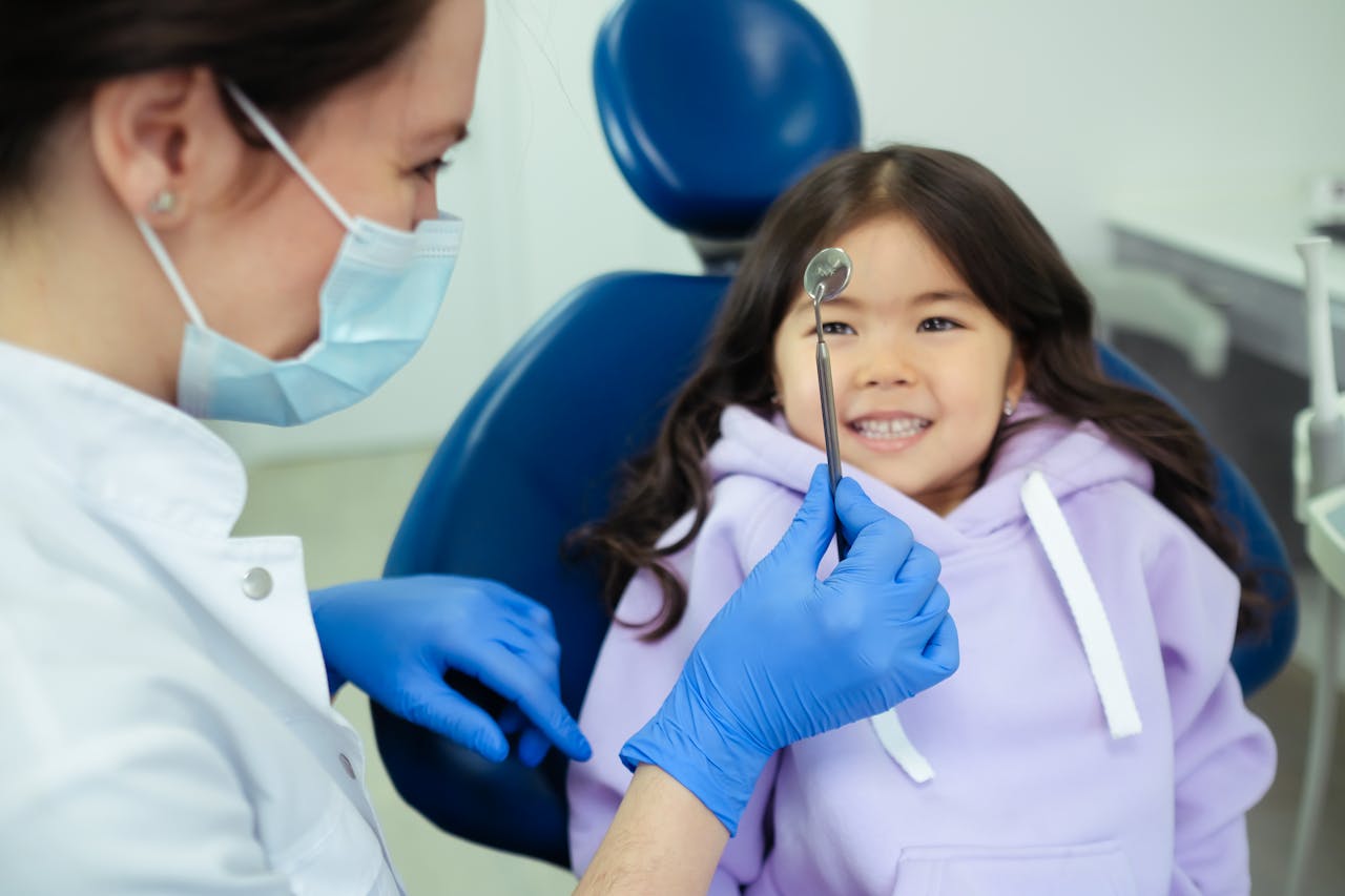 Dentist examining smiling child with dental mirror at Keller & Wainwright Orthodontics in Sunnyvale, CA